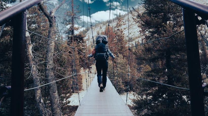 A backpacker crossing a suspension bridge in the high Sierra
