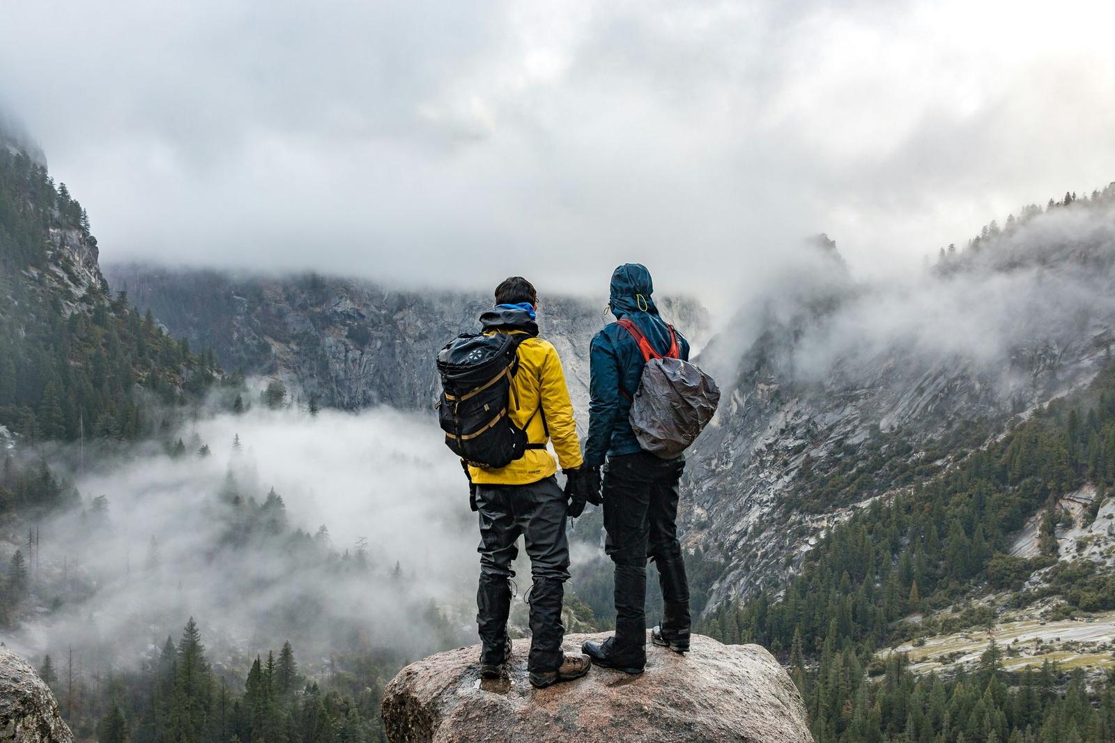 Two hikers looking out over a valley filled with cloud